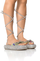 OUTSHINE EMBELLISHED BOW LACE UP FLAT SANDAL IN HOLO